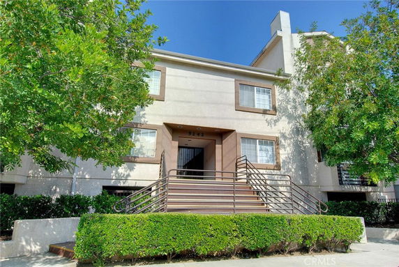 Front view of a two-story residential building with a central entrance and surrounding greenery.
