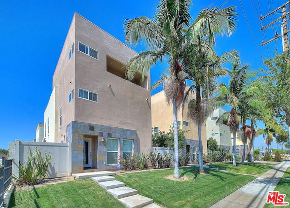 Front view of a multi-story modern house with a small lawn and pathway.