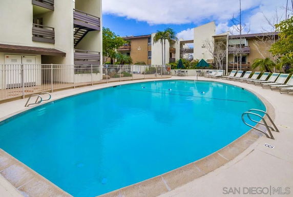 Outdoor swimming pool area with lounge chairs and surrounding buildings.