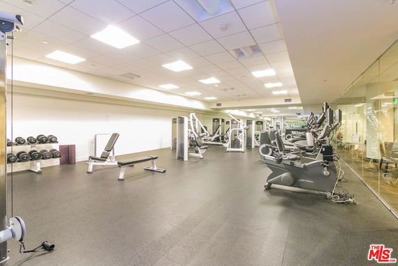 Indoor gym area with exercise equipment and weights.