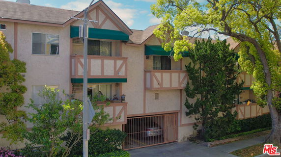Front view of a multi-story residential building with balconies and parking.