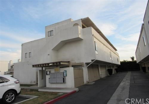 Front view of a modern multi-story building with a flat roof and overhanging balconies.