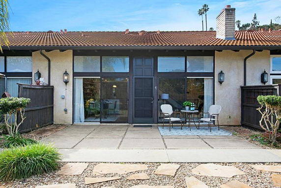 Front view of a house with large windows and a small patio area.