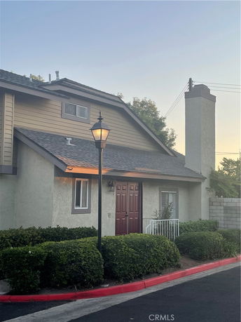 Front view of a two-story house with a chimney and red door.