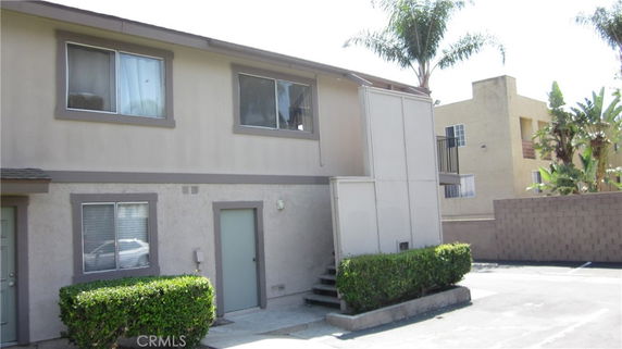 Front view of a two-story house with beige exterior and multiple windows.