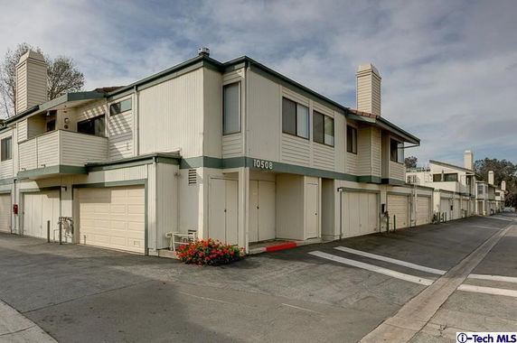 Front view of a multi-story building with garage spaces.