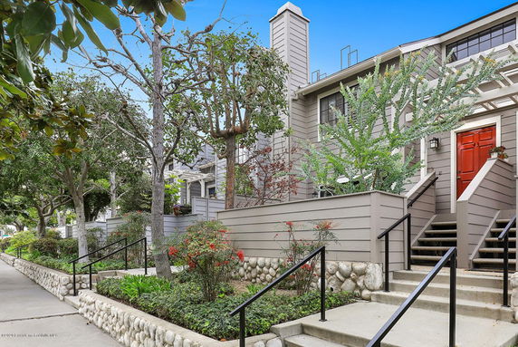 Front view of a multi-story house with a sloped path and stairs leading to the entrance.