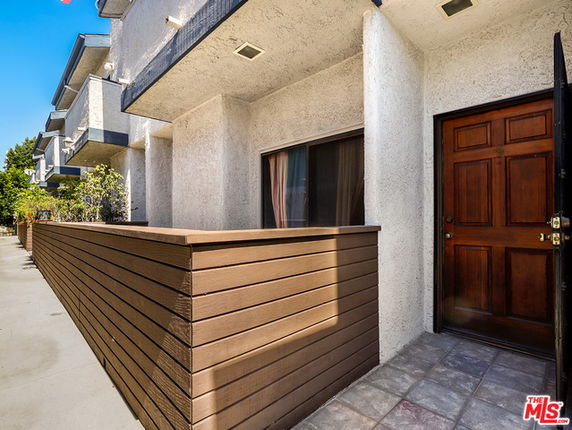 Front view of a building with a wooden fence and a tiled entryway.
