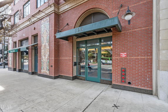 Front view of a brick building entrance with glass doors and decorative tile columns.