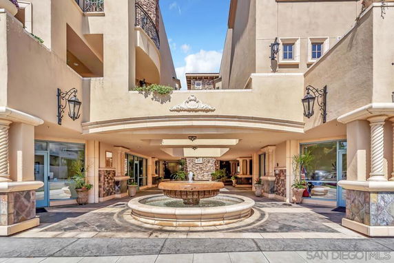 Front view of a multi-story building with an entrance canopy and a decorative fountain.