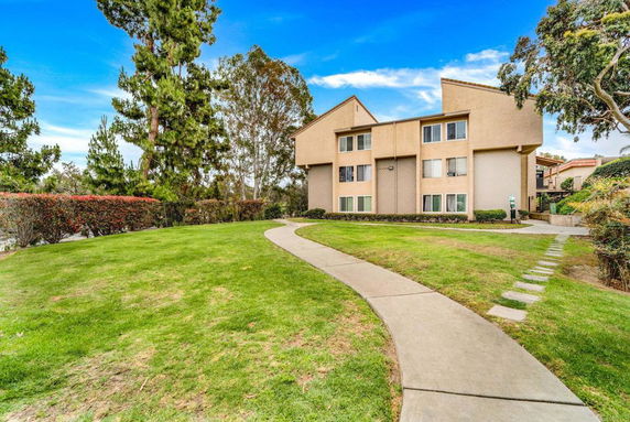 Front view of a multi-story residential building with a pathway leading to it.