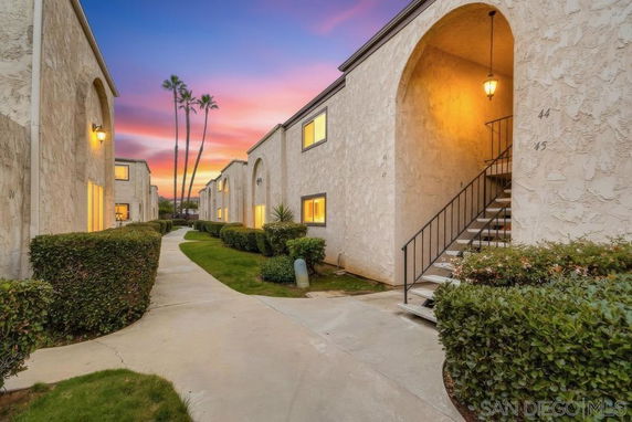 Front view of a residential building with outdoor stairs and archway.