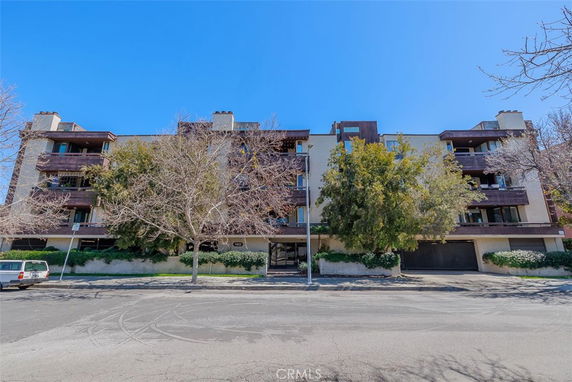 Front view of a multi-story residential building with balconies and garages.