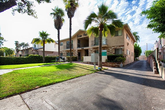 Front view of a two-story apartment building with palm trees.