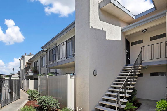 Front view of a multi-story residential building with outdoor stairs and balconies.