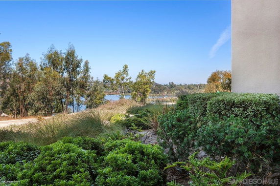 Partial view of a building with surrounding greenery and a distant water body.