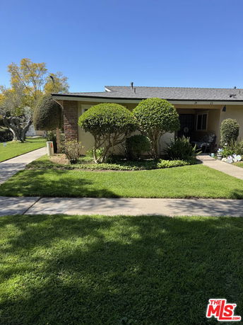 Front view of a single-story house with a landscaped yard and trimmed bushes.