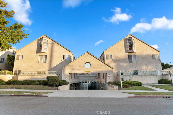 Front view of a residential complex with triangular roof design and gated entrance.