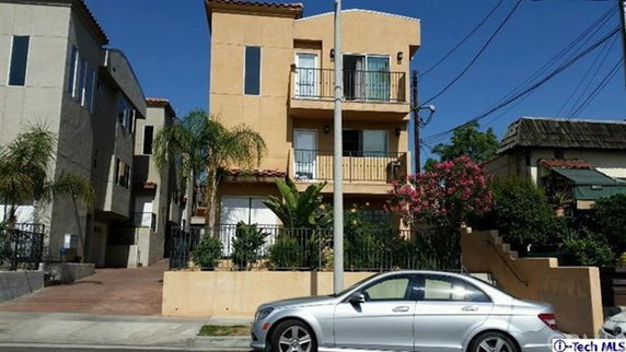 Front view of a three-story residential building with balconies and a driveway.
