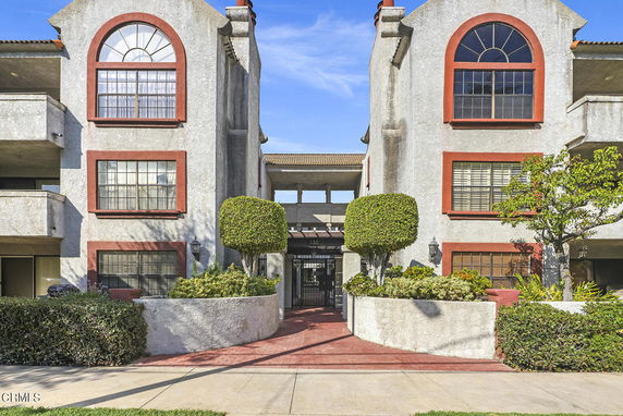 Front view of a multi-story residential building with arched windows and a central entrance.