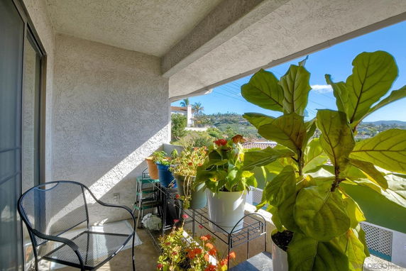 Balcony with potted plants and outdoor seating, overlooking a scenic view.