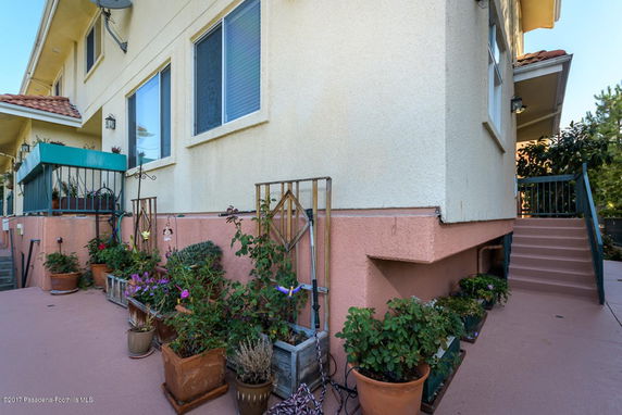 Side view of a house exterior with potted plants and stairs