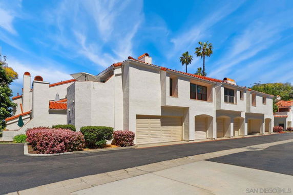 Side view of a multi-story residential building with garages.