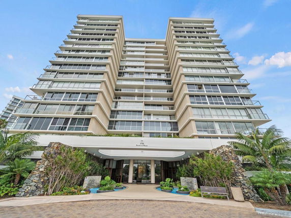 Front view of a multi-story building with large glass windows and balconies.