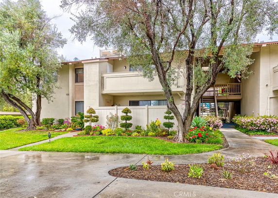 Front view of a multi-story residential building with balconies and landscaped garden.
