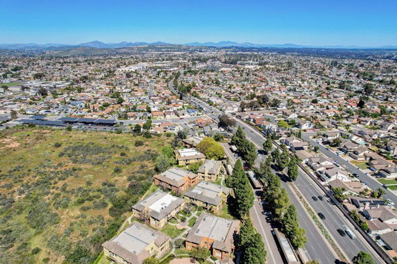 Aerial view of a residential area with houses, roads, and surrounding greenery.