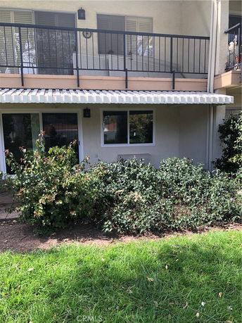 View of a house with a balcony and awning, featuring sliding doors and a window on the lower level.