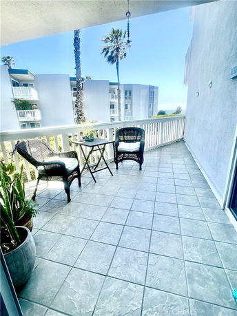 Balcony view overlooking nearby buildings with visible palm trees.
