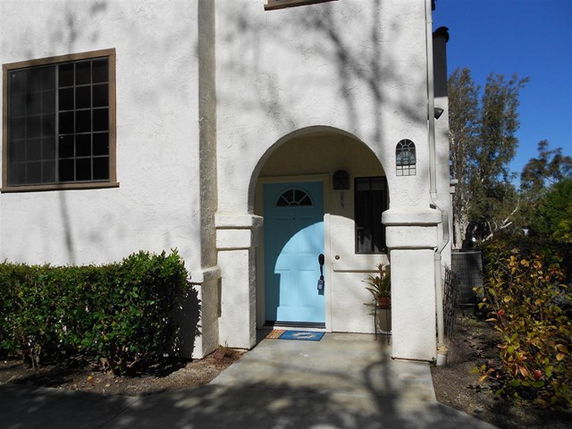 Front view of a house with a blue arched door and a window above a pathway.