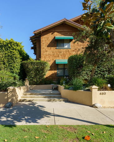 Front view of a two-story house with wood siding and green awnings.
