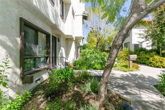 Front view of a two-story house with a pathway and surrounding greenery.