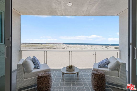 View from a balcony overlooking a sandy beach and ocean.