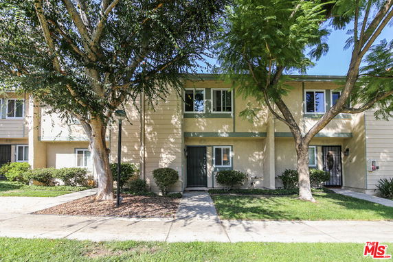 Front view of a two-story building with multiple units and a walkway.