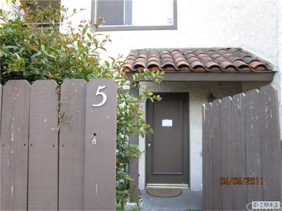 Front view of a house with a wooden fence and a brown door.