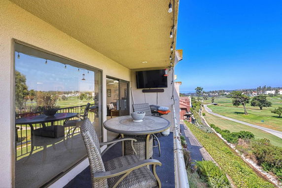 Panoramic view from a balcony overlooking a golf course and surrounding landscape.