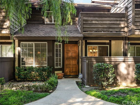 Front view of a two-story townhouse with wooden exterior and small garden.