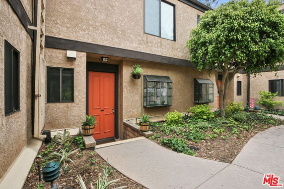 Front view of a building with a red door and multiple windows.