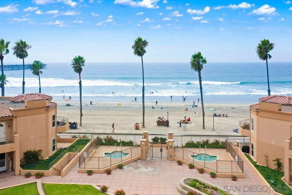 Panoramic view of a beachfront area with buildings, palm trees, and the ocean.
