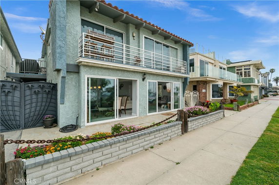Front view of a two-story house with a balcony and large glass sliding doors.