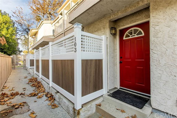 Front view of a townhouse with a red door and white fence.