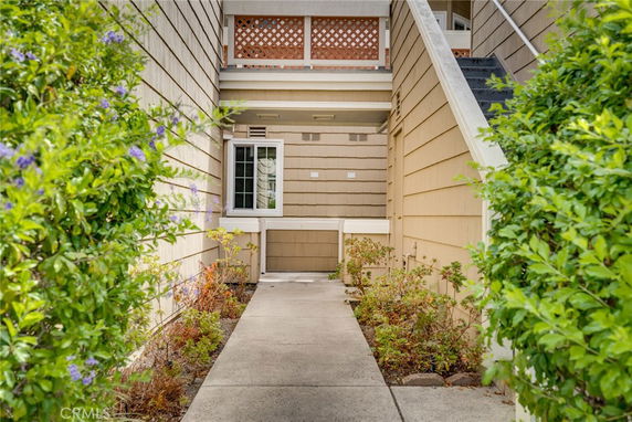 Entrance path leading to a multi-level residential building with balconies.