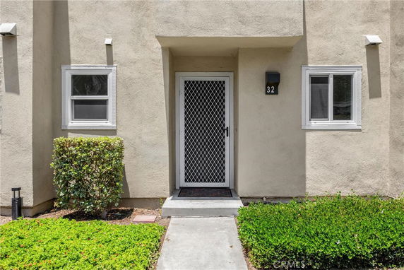 Front view of a house entrance with a security door and two windows.