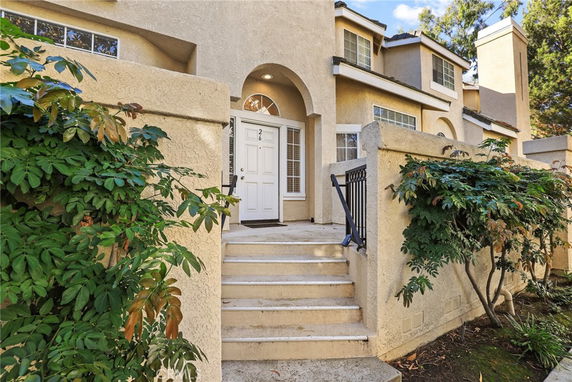 Front view of a house with multiple levels and stairs leading to the entrance.
