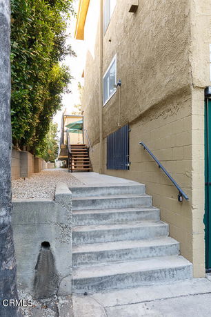 Side view of a multi-story building with a staircase leading to an entrance.
