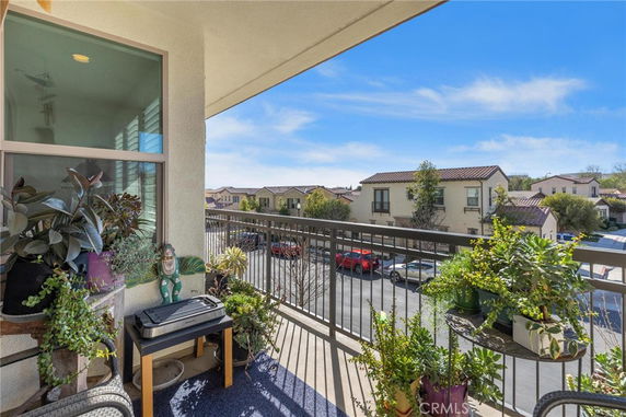 Balcony overlooking residential neighborhood with nearby houses and parked cars.