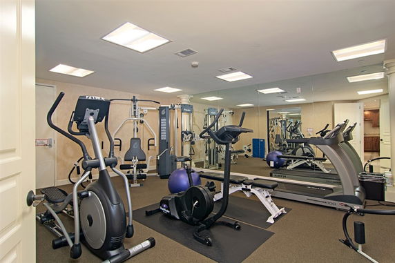 Indoor gym with exercise equipment including treadmills, elliptical, and weight machines.